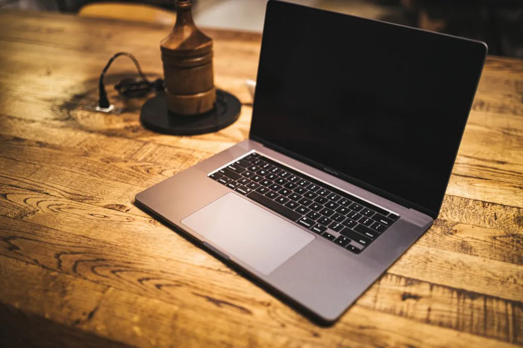 木製のデスク上に置かれたノートPCとランプ